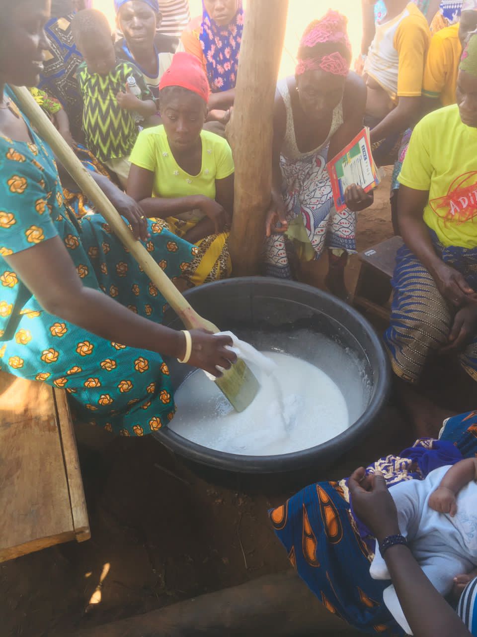 Woman stirring a large vat of artisanal shea butter
